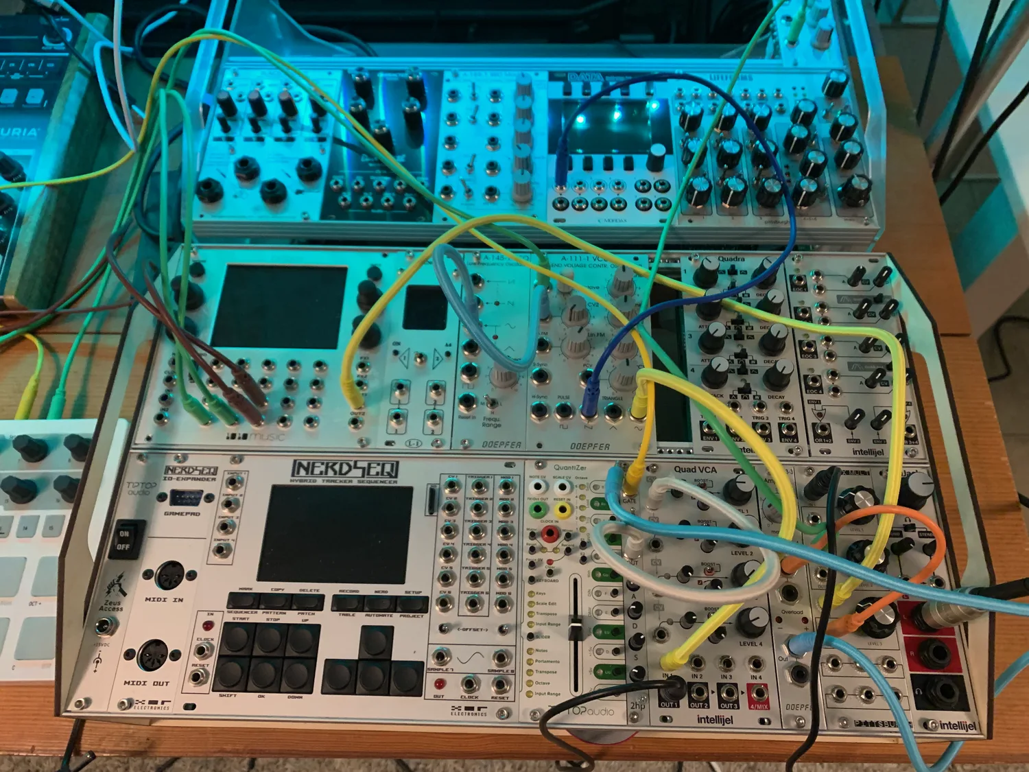 A powered eurorack on the bench, full of modules and patch cables under blue light.