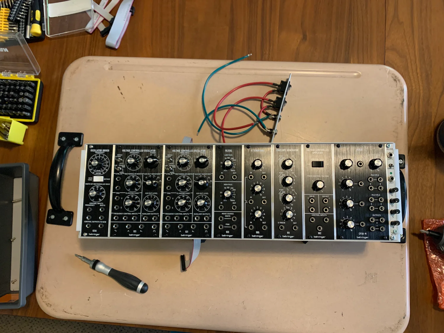 The finished Rev 2 case on the bench: a single row of synth modules mounted with side handles, patch cables running out the back.